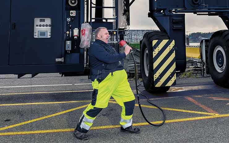 Employee of the PORT OF KIEL with cable in hand in front of a crane